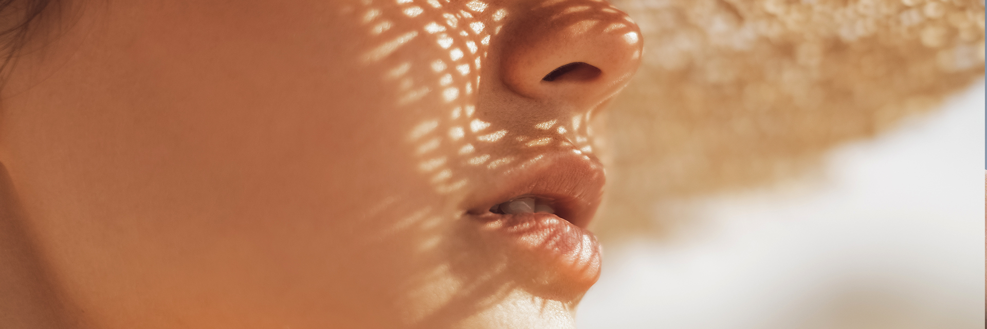 Mujer previniendo los rayos UVA/UVB con un Hidratante SPF Facial y un sombrero de paja.